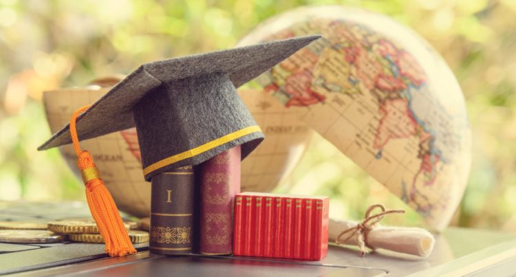 Key success in graduate study abroad program and open or expand world view experience concept : Graduation cap or hat, certificate or diploma, mini text books on a laptop computer, a half world globe.
